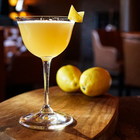 Forestil dig, at du træder ind i en sofistikeret bar i 1920’ernes Paris – jazzmusikken spiller, og stemningen emmer af glamour. Her bliver Sidecar født, en cocktail med lige dele elegance og attitude. Navnet siges at stamme fra en lidt for festlig gæst, der blev kørt hjem i en motorcykels sidevogn efter en aften med lidt for mange af disse lækre drinks. Med sin perfekte balance mellem syrlig citron, sød Cointreau og varm cognac er Sidecar ikke bare en drink – det er en tidsrejse til en æra af dekadence og charme.

Glas: [https://www.hjhansen-vin.dk/glas-tilbehoer/alle-riedelprodukter/bar-collection/sour-bar-drinks-specifik-glasserie-6417-06-2-pack|Riedel Sour Bar Glas]
Pynt: Citronpeel

[https://media-prod.hjhansen-vin.dk/download/link/70c1cfc6-6a24-433a-a38b-b7b89ff623bf|Download opskrift]